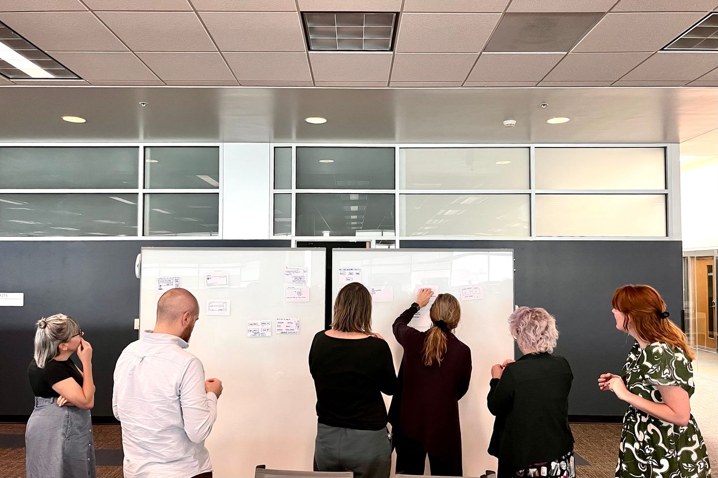 Several people viewing sketches on whiteboards
