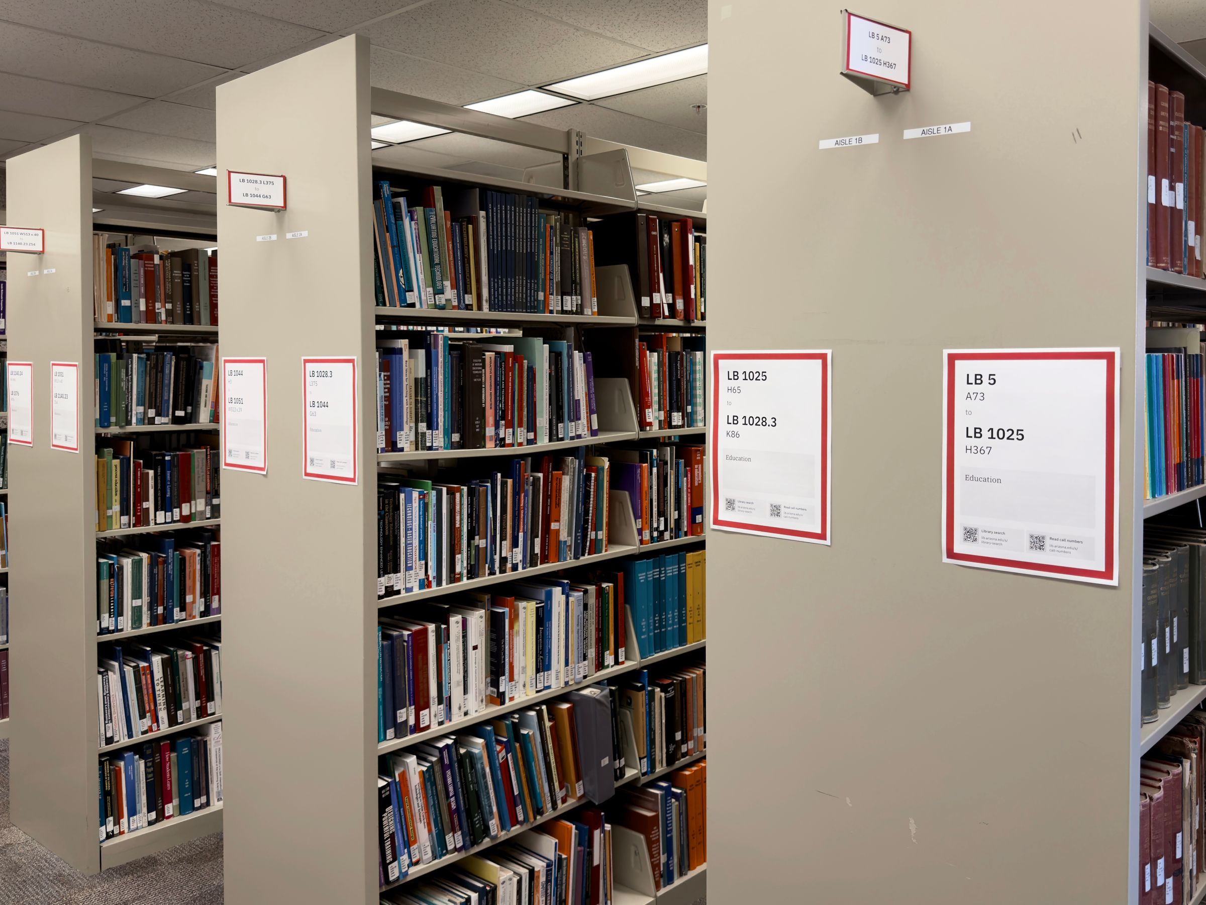 Library stacks full of books with both new signs installed