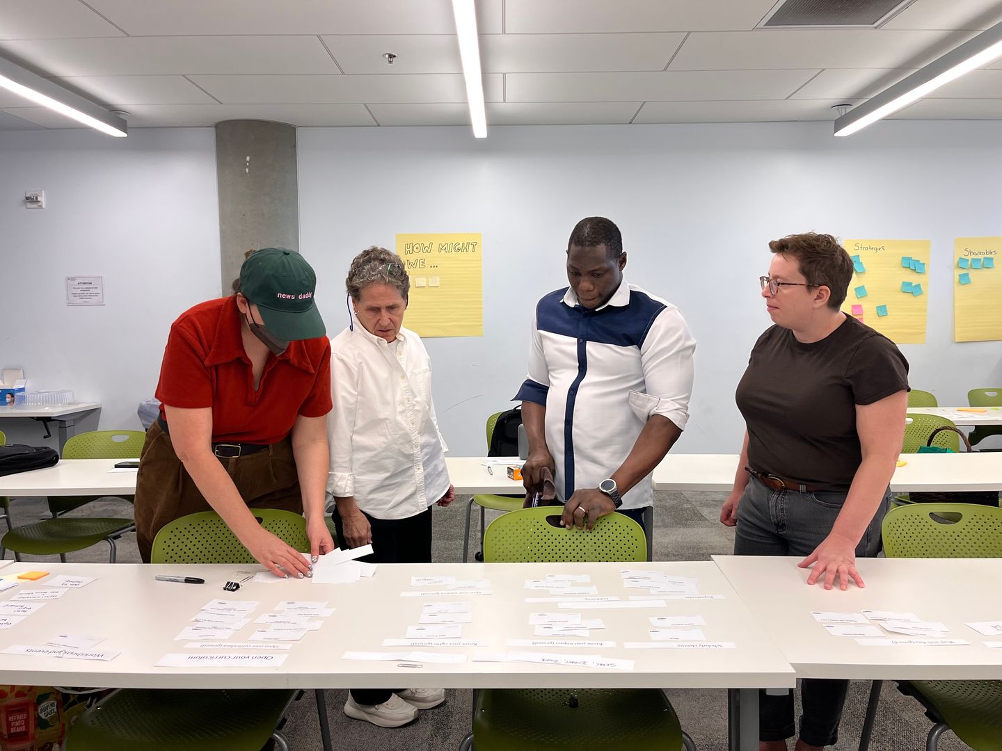 Four people organizing small pieces of paper in front of a desk